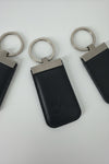 A black leather key fob case with an embossed logo, attached to a silver metal split ring, shown on a plain white background.