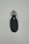 A black leather key fob or keychain with silver-tone metal rings and a snap button, shown on a plain light gray background.